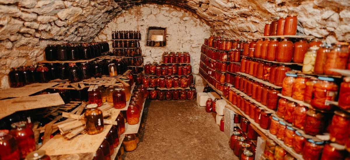 A cozy stone cellar filled with neatly arranged jars of preserves.