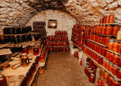 A cozy stone cellar filled with neatly arranged jars of preserves.