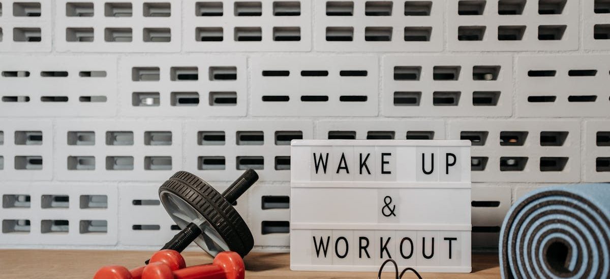 Fitness gear and motivational sign in home gym setup against a brick wall.